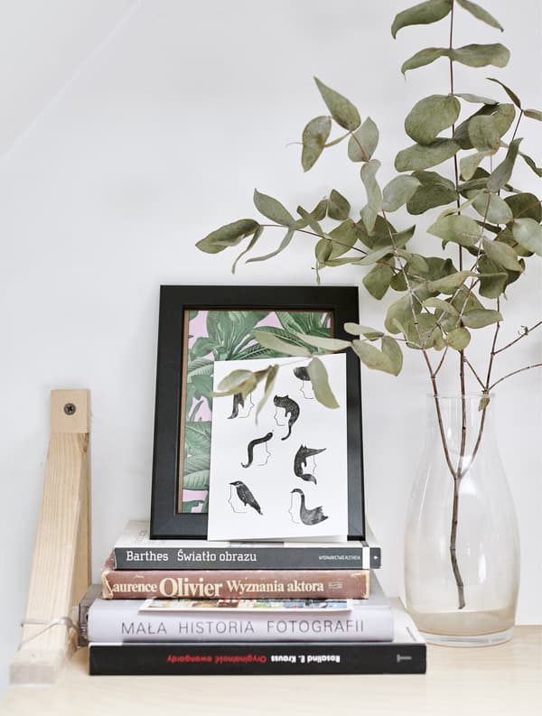 Présentation sur une tablette murale, avec livres, images et vase.