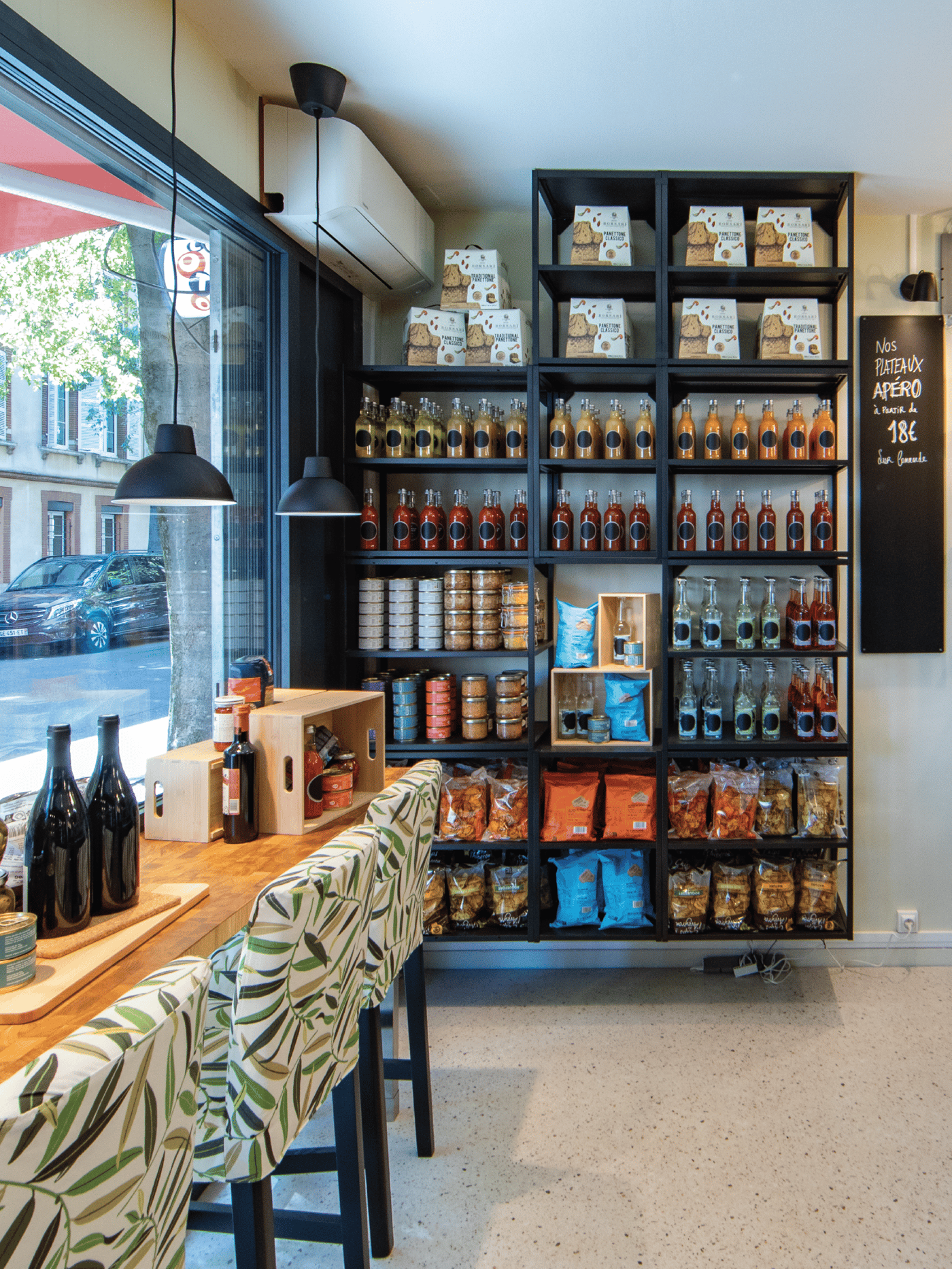 Présentoir noir contre un mur mettant en avant des produits alimentaires dans une épicerie fine.
