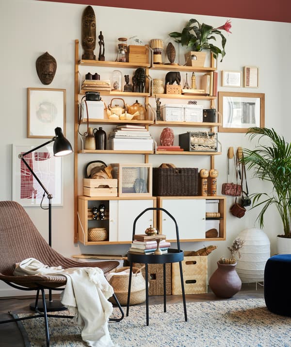 Prestatges IKEA SVALNÄS en una paret d’una sala, decorats amb objectes de viatges.