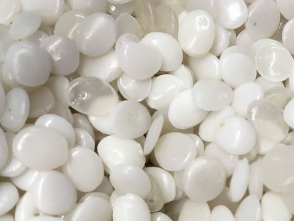 Prezentare mărită a peletelor din plastic PLA albe și transparente fabricate din materiale regenerabile.