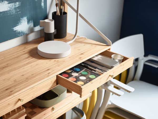 Primer pla d'una prestatgeria IKEA SVALNÄS, amb un calaix estret obert on hi ha aquarel·les i materials de manualitats.