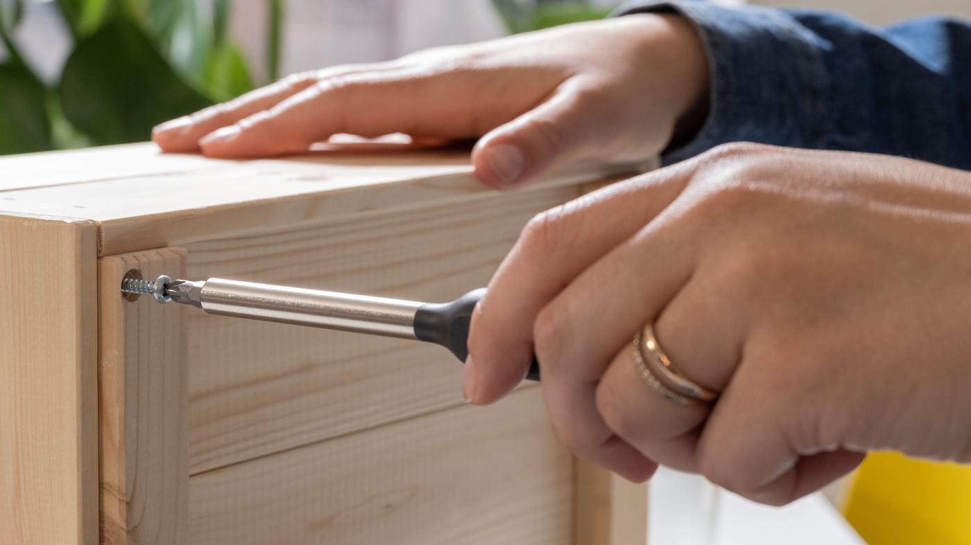 Primer plano de dos manos reparando un mueble.