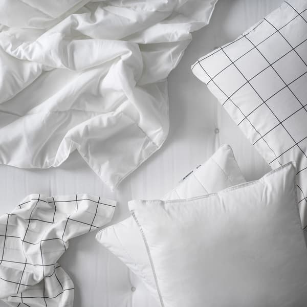 Primer plano de ropas de camas blancas sobre un colchón blanco. Se aprecian sábanas, edredones y almohadas.