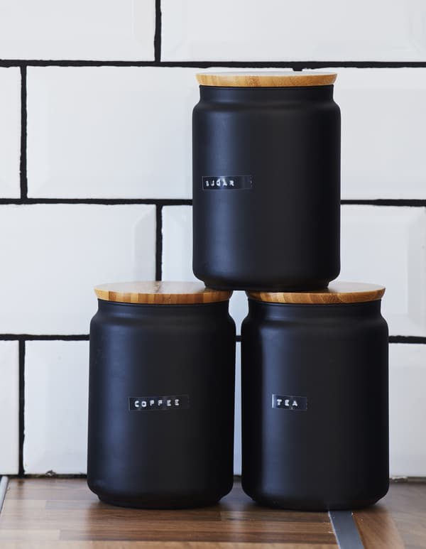 Printed labels on three black jars.