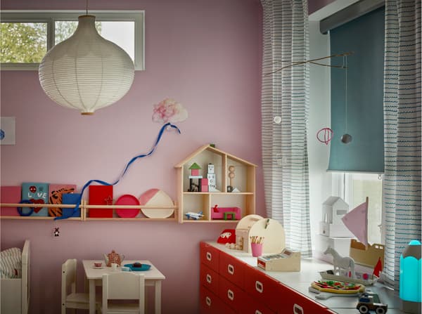 Prozor dečje sobe sa zelenim/belim prugastim zavesama i svetloplavim rol-zastorom za zamračivanje, spuštenim do pola prozora.