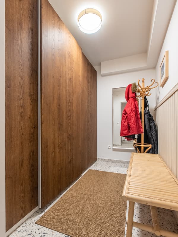 Przedpokój z brązową szafą PAX z drzwiami przesuwnymi. Drzwi szafy są zamknięte.