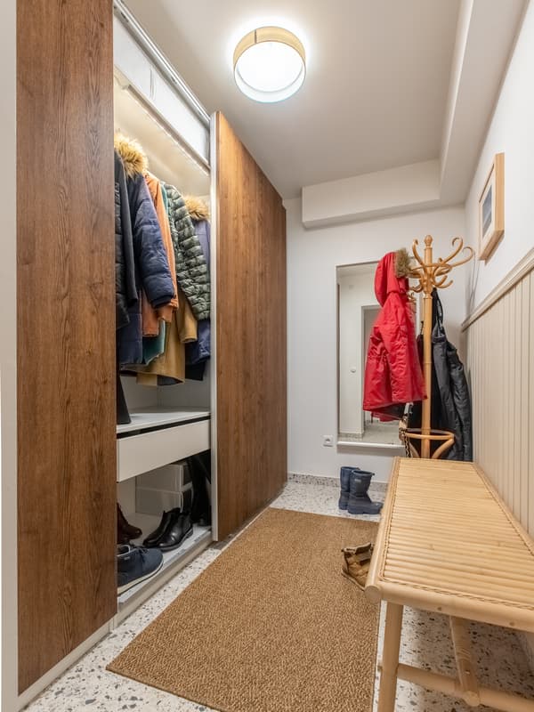 Przedpokój z brązową szafą PAX z drzwiami przesuwnymi. Drzwi szafy są otwarte