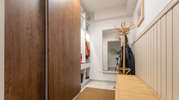 Przedpokój z brązową szafą PAX z drzwiami przesuwnymi. Jednak z szaf jest otwarta i ma włączone oświetlenie wewnętrzne.