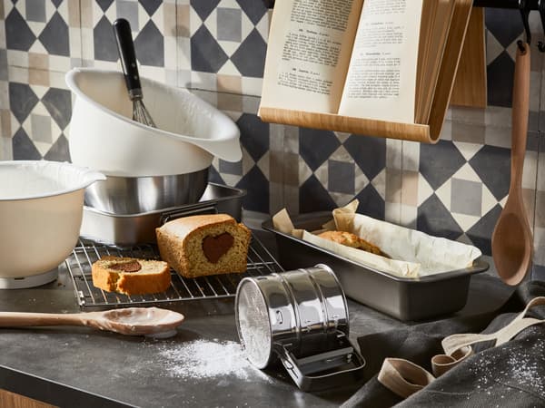 Przesiewaczka do mąki, miski i inne akcesoria do pieczenia na blacie kuchennym.