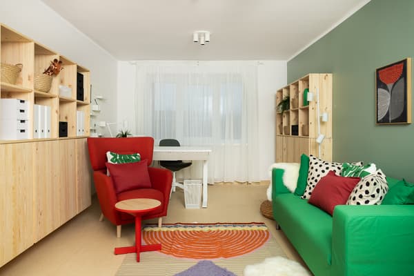 Psihologa kabinets pēc interjera pārvērtībām ar zaļu dīvānu, sarkanu krēslu un IKEA plauktiem.