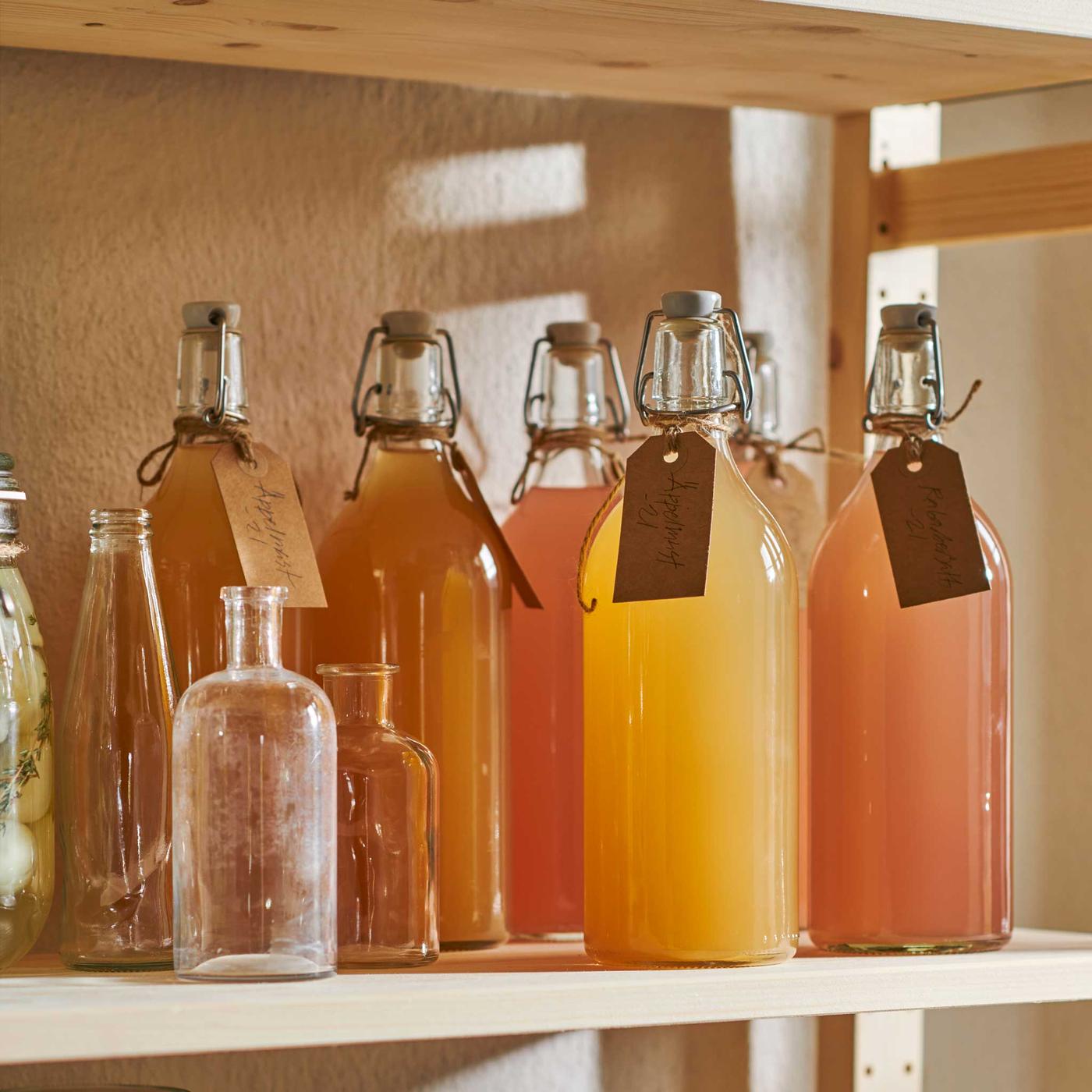 Puisella hyllyllä on KORKEN-pulloja, joissa keltaisia ja oransseja juomia 
