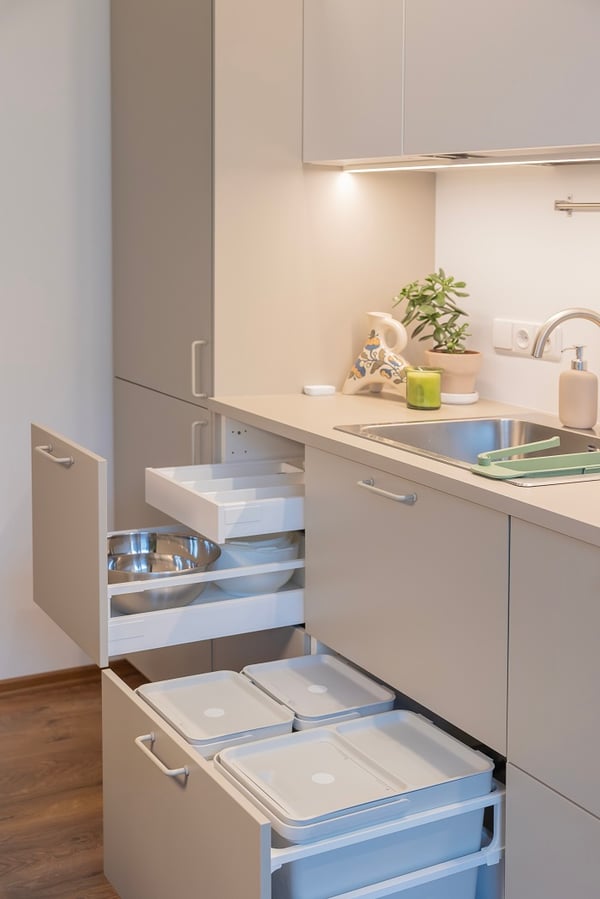 Pull-out kitchen drawers with bowls, utensils, and recycling bins.