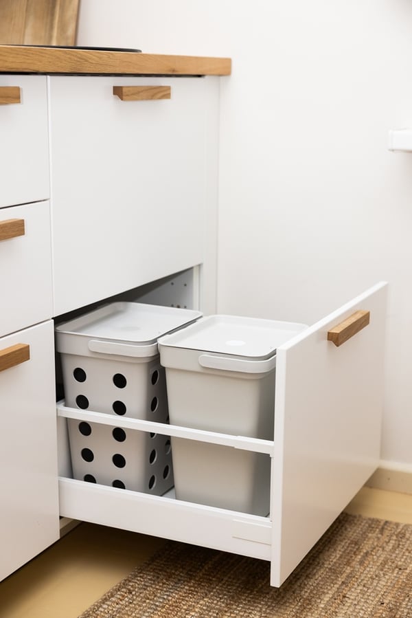 Pull-out waste sorting system inside a kitchen cabinet.