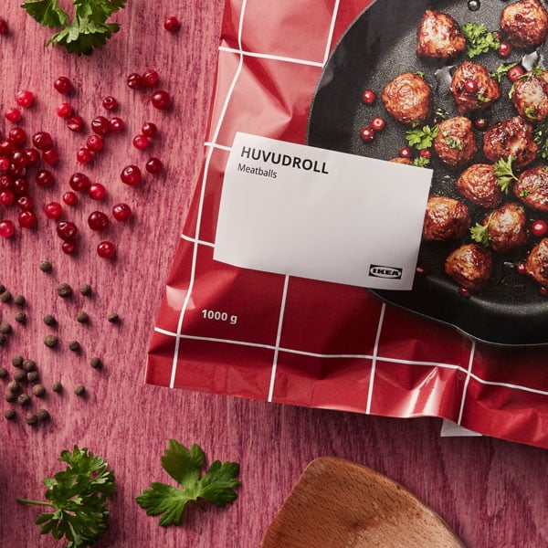 Punainen HUVUDROLL lihapyörykkä -pussi pöydällä, jossa mausteita ja yrttejä.