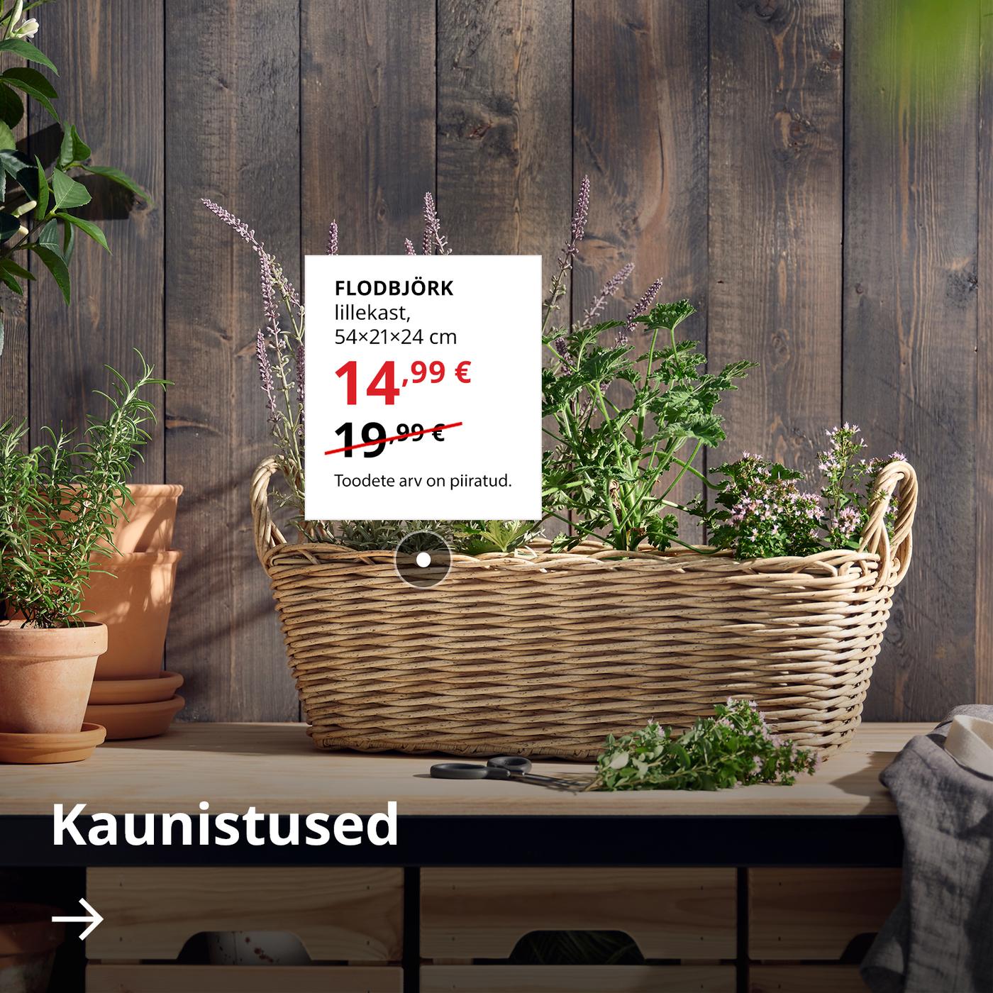 Punutud FLODBJÖRK lillekast seisab puidust seina ääres. Selle kõrval valgel taustal on kuvatud väljamüügi erihind 14,99 € (tavahind 19,99 €). All on nool tekstiga „Kaunistused“.