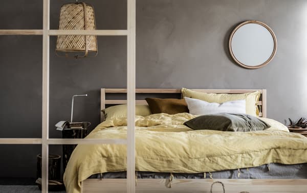 Quarto minimalista com paredes cinzentas e um esquema de cores suaves, detalhes em madeira, uma cama de casal TARVA e um candeeiro KNIXHULT.