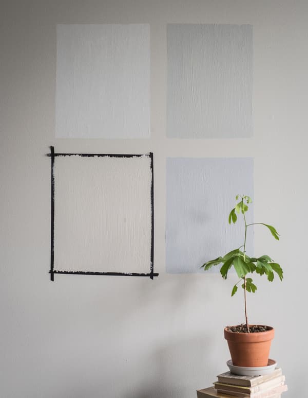 Quatre carrés peints dans des couleurs différentes sur un mur gris.