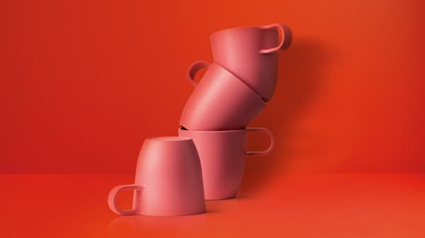 Quatre tasses vermelles apilades sobre un fons vermell