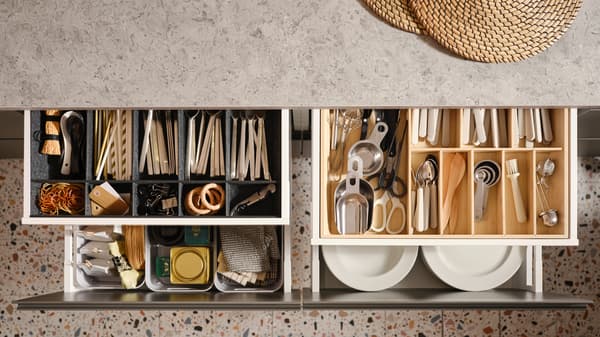 Quattro cassetti della cucina MAXIMERA aperti con vari oggetti in un portaposate, un portatutto regolabile per cassetto e contenitori - IKEA.