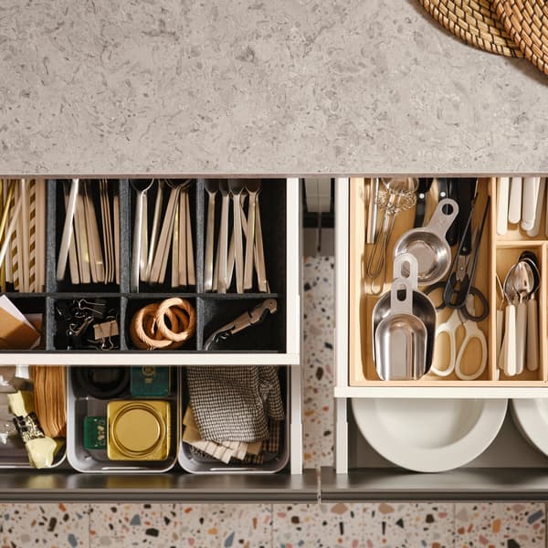 Quattro cassetti della cucina MAXIMERA aperti, contenenti oggetti di vario tipo in un portaposate, un portatutto regolabile per cassetto e alcuni contenitori.