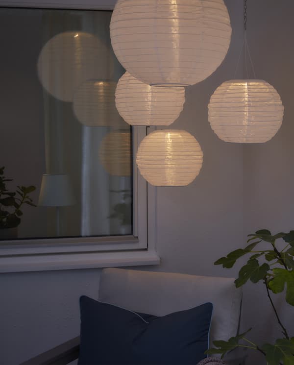 Quattro lampade a sospensione bianche a energia solare creano la giusta illuminazione in uno spazio esterno in penombra - IKEA