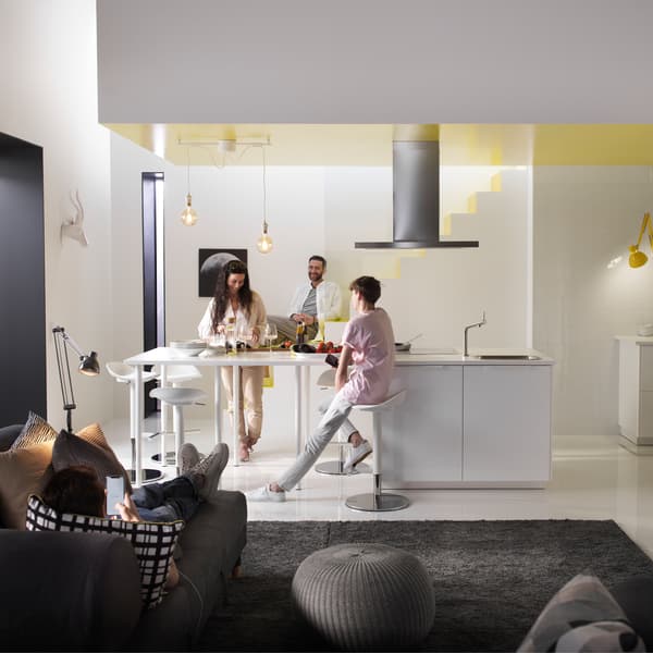 Quattro persone in una cucina soggiorno. Una è sdraiata sul divano mentre guarda uno smartphone, le altre 3 sono in cucina e stanno ridendo tra loro. Sul pavimento, c'è un pouf SANDARED di colore grigio.