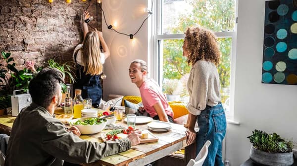 Quattro persone sedute attorno a un tavolo da pranzo che ridono e scherzano tra loro - IKEA Family.