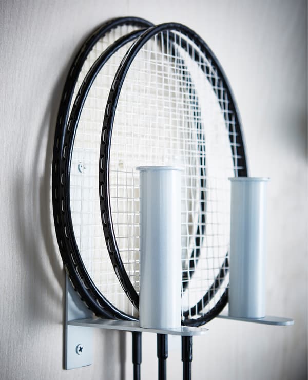 Racquets held by GRUNDTAL toilet roll holders on the wall.