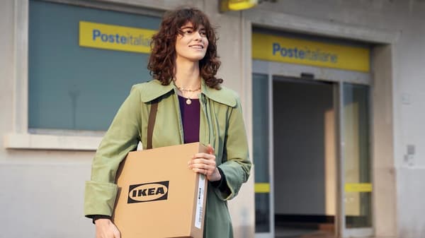 Ragazza appena uscita da un ufficio postale con un pacco piatto IKEA sotto il braccio