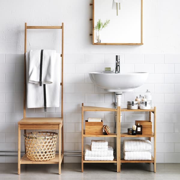 RÅGRUND bamboo chair with towel rack next to RÅGRUND bamboo sink shelf in a white bathroom.