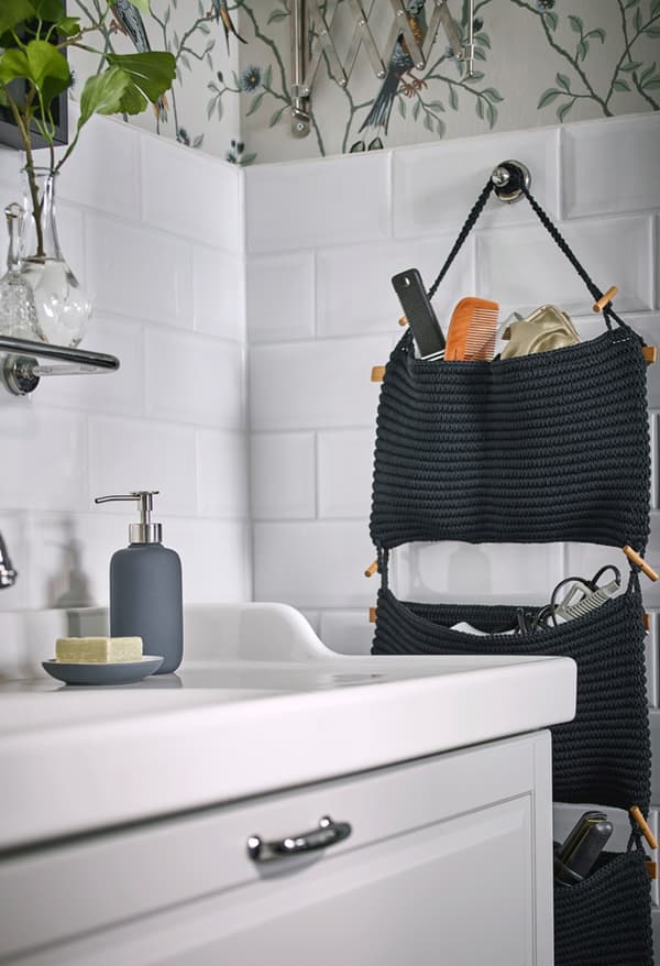 Rangement suspendu NORDRANA en gris foncé fixé au mur d'une salle de bain carrelée de blanc