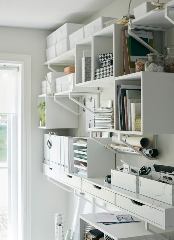 Rangements IKEA EKBY blancs, étagères murales et tiroirs permettant d’organiser les fournitures de bureau et les livres.
