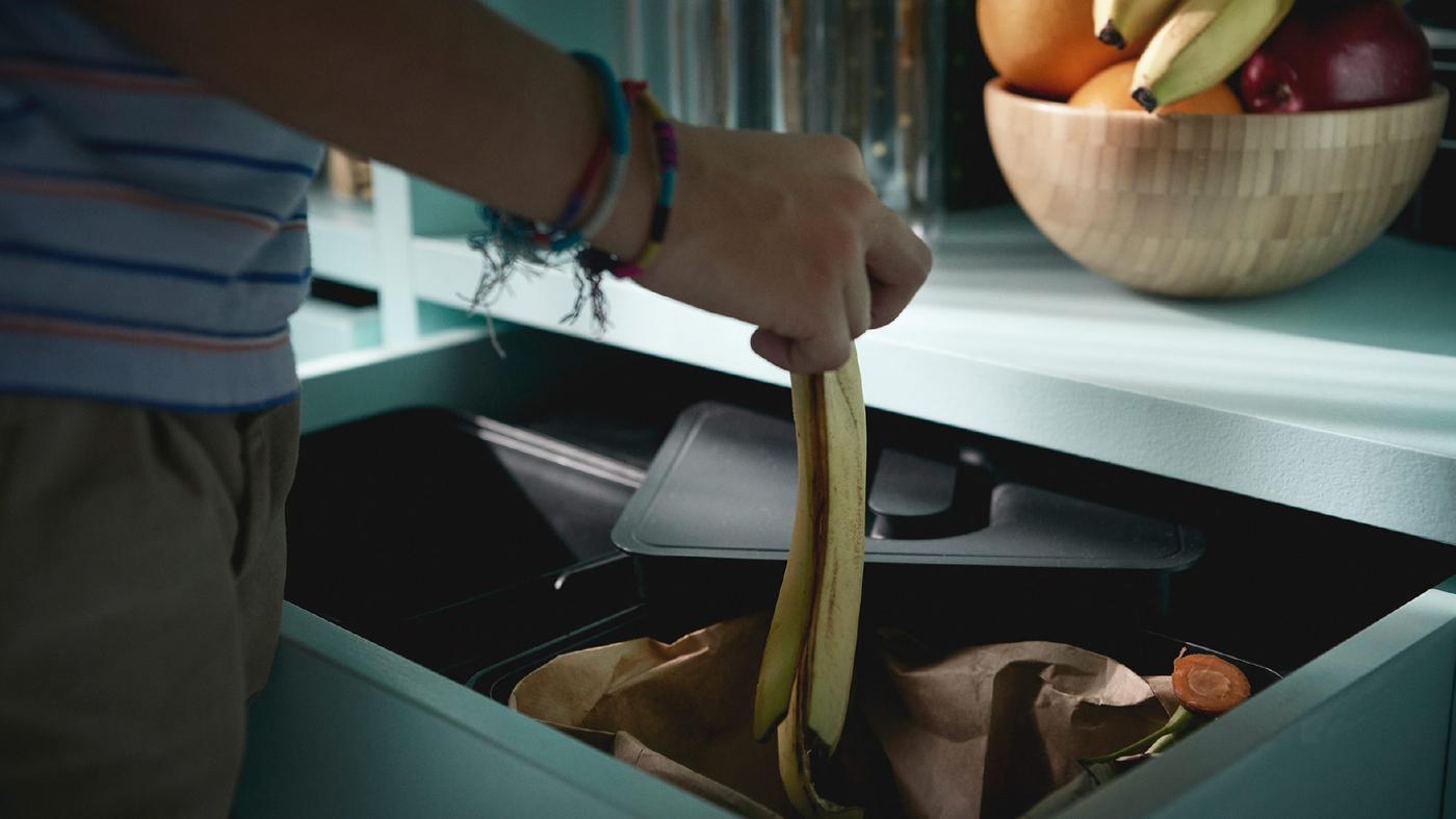 Rapaz com pulseiras, a colocar uma casca de banana no sistema de reciclagem VARIERA.