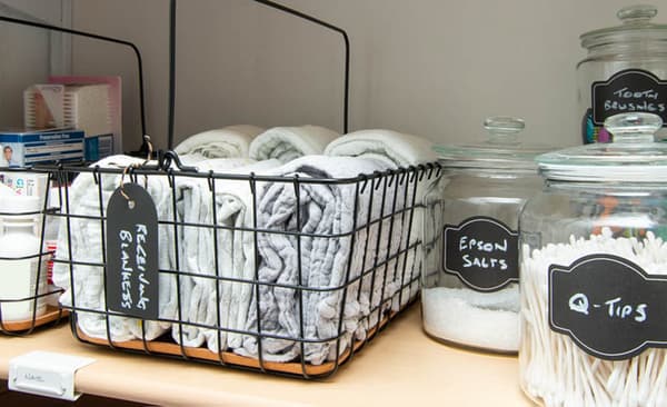 Receiving blankets and baby toiletries, stored in black PLEJA wire baskets.
