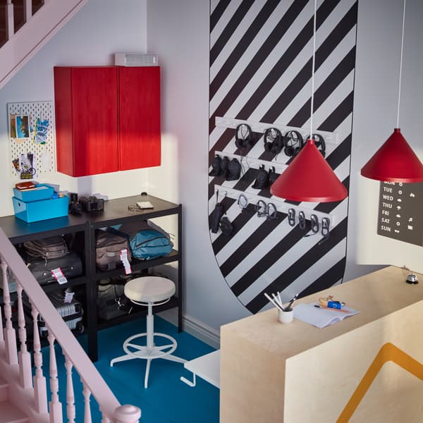 Recepcja z ladą z jasnego drewna, zawieszonymi nad nią czerwonymi lampami i ustawionymi w tylnej części szafkami.