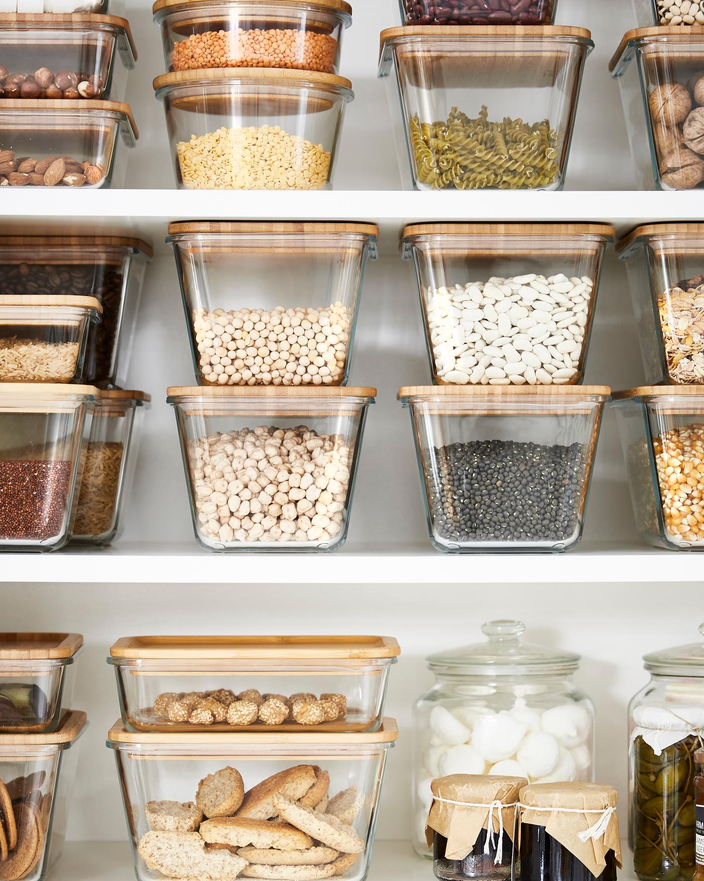 Recipientes para alimentos em vidro com tampas em bambu, empilhados uns por cima dos outros, todos repletos de diferentes tipos de alimentos