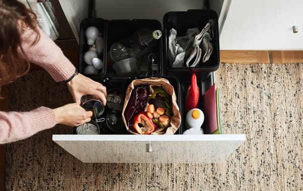 Recycling sorted into plastic boxes inside an open drawer.