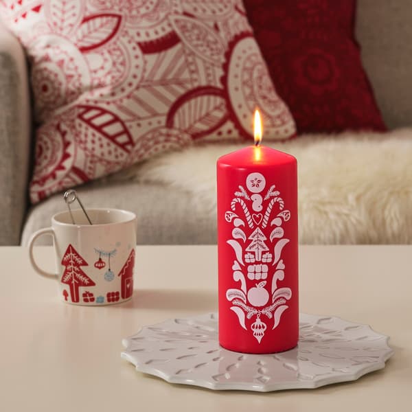 Red candles on  a black table besides the Christmas tree and gifts.