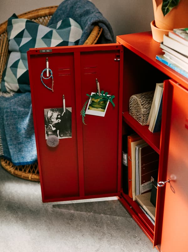 Red IVAR cabinet in a student bedroom, with one of the doors open and pictures hung on the inside.