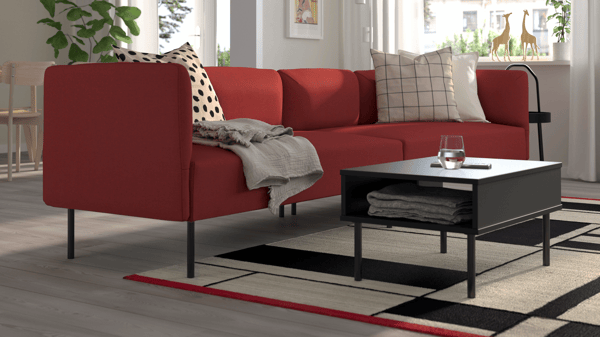 Red LILLEHEM 3-seater sofa with black legs in a bright living room, paired with black-and-white coffee table and patterned rug.