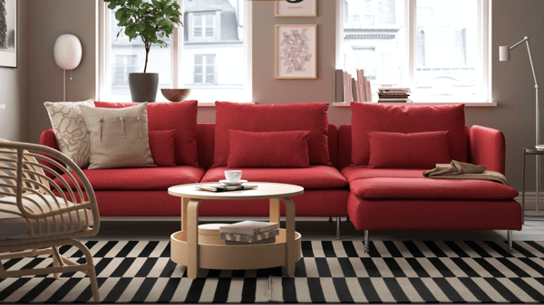 Red SÖDERHAMN modular sofa in vibrant setting with striped black-and-white rug, rattan armchairs, and mix of red and green cushions.