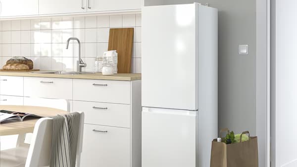 Réfrigérateur en pose-libre à côté d'une cuisine blanche