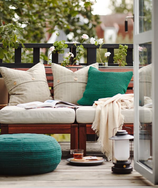 Reggeli az erkélyen, nyitott ajtókkal és sok párnával, takarókkal és kültéri bútorokkal.