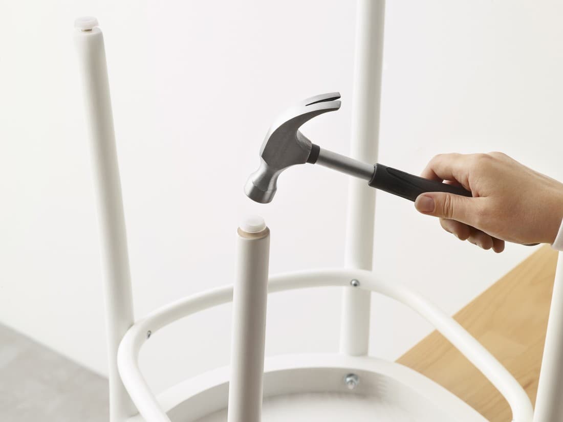 ręka z młotkiem naprawia krzesło