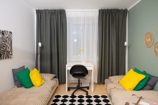 Relaxation and study area in a family room with two beds, desk chair, and curtains.
