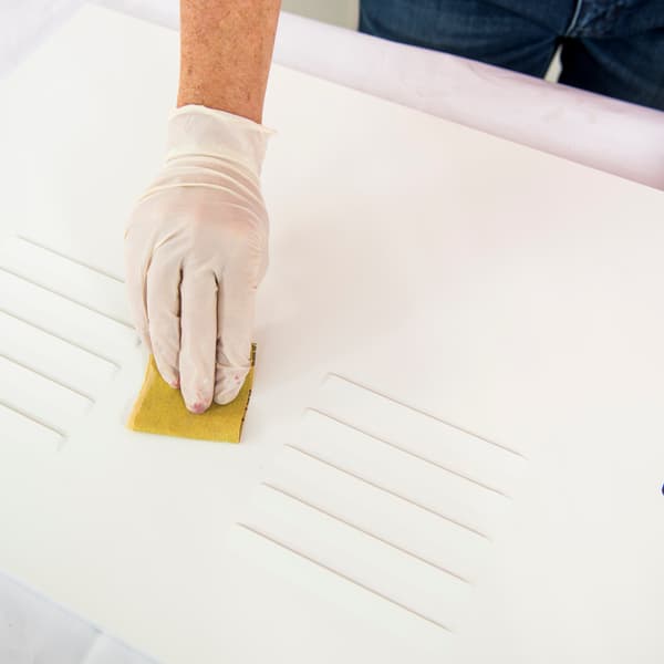 Remove the cabinet doors, degrease the metal, then lightly sand the doors.