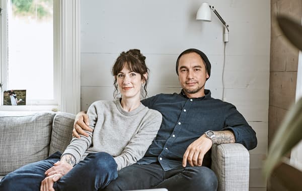 Rena e Sam seduti sul divano nel loro casale in Norvegia.