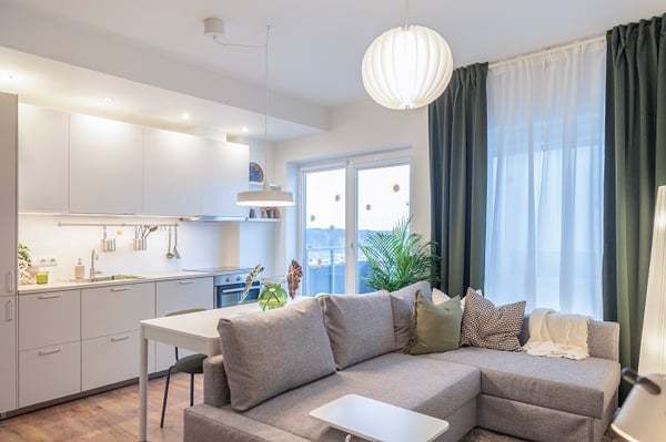 Renovated open-plan living room with grey sofa and modern kitchen.