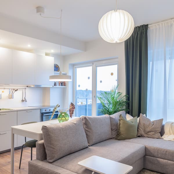 Renovated open-plan living room with grey sofa and modern kitchen.