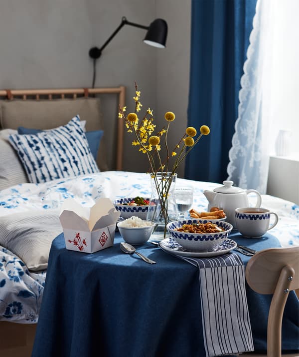 Repas pour une personne préparé avec soin. Look oriental, bols multiples, le tout posé sur une petite table ronde près d’un lit.